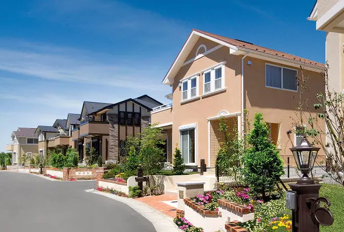 作業着姿の男性が外壁にメモを取りながら点検作業をしている様子